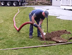 Septic pumping technician servicing a residential septic tank with a vacuum hose in Philadelphia, PA