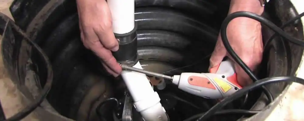 Sump pump installation technician connecting PVC discharge piping in Philadelphia, PA